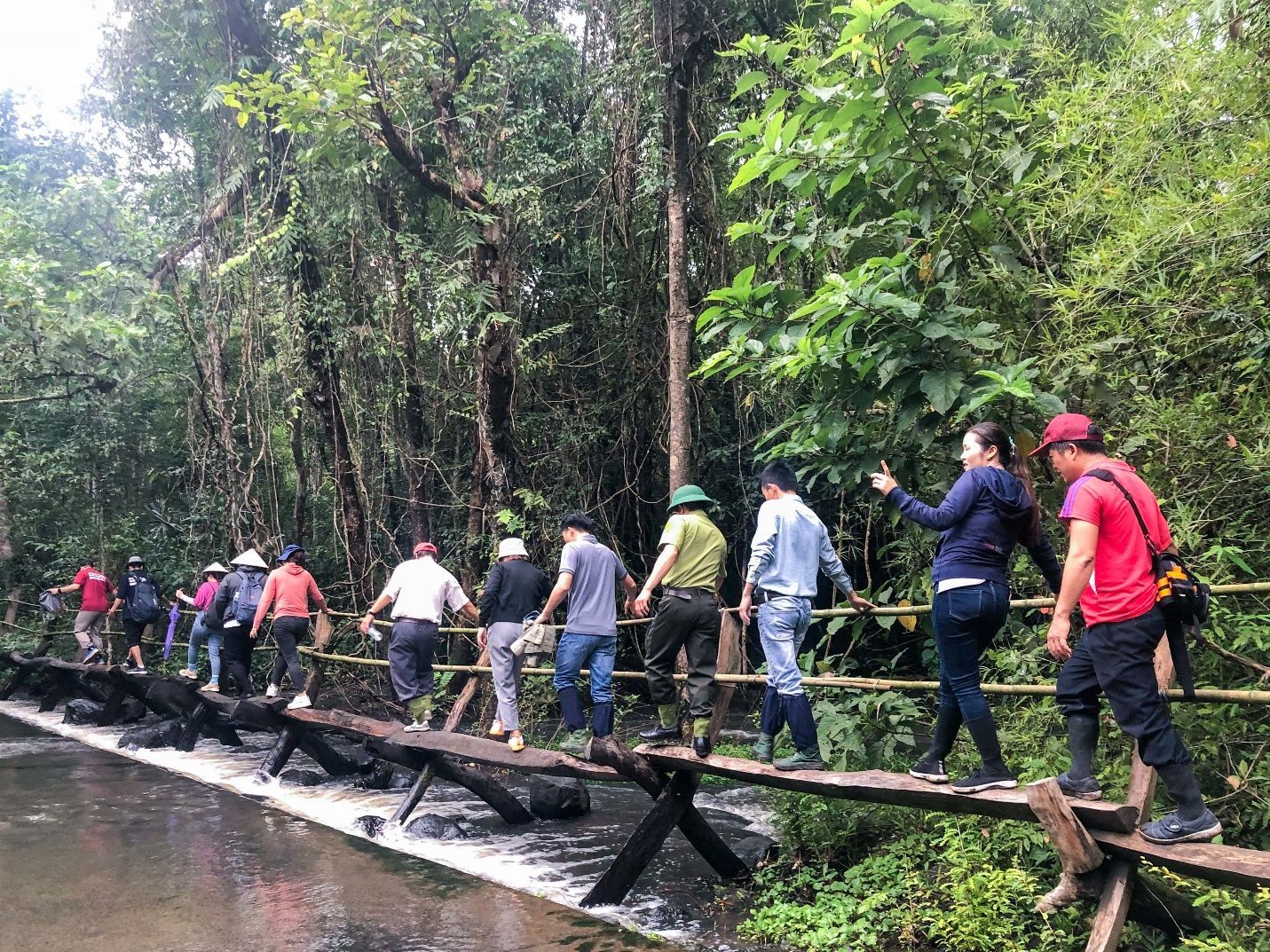A group of people standing on a bridge over a river Description automatically generated with low confidence
